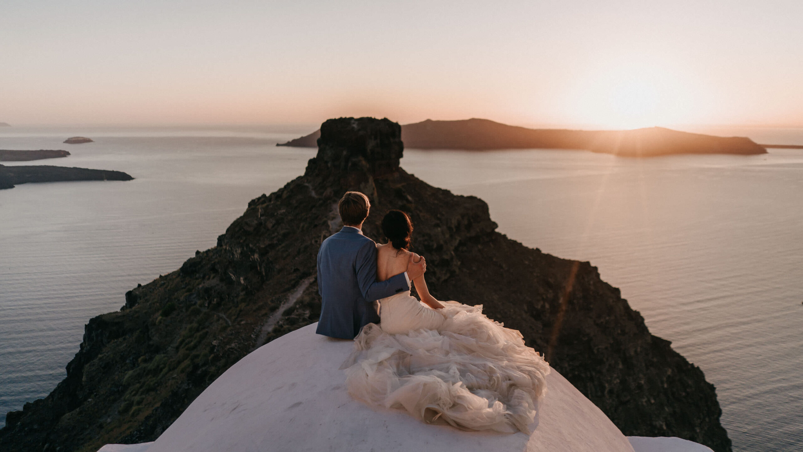 Couple in low golden light on the Santorini caldera during a wedding session.