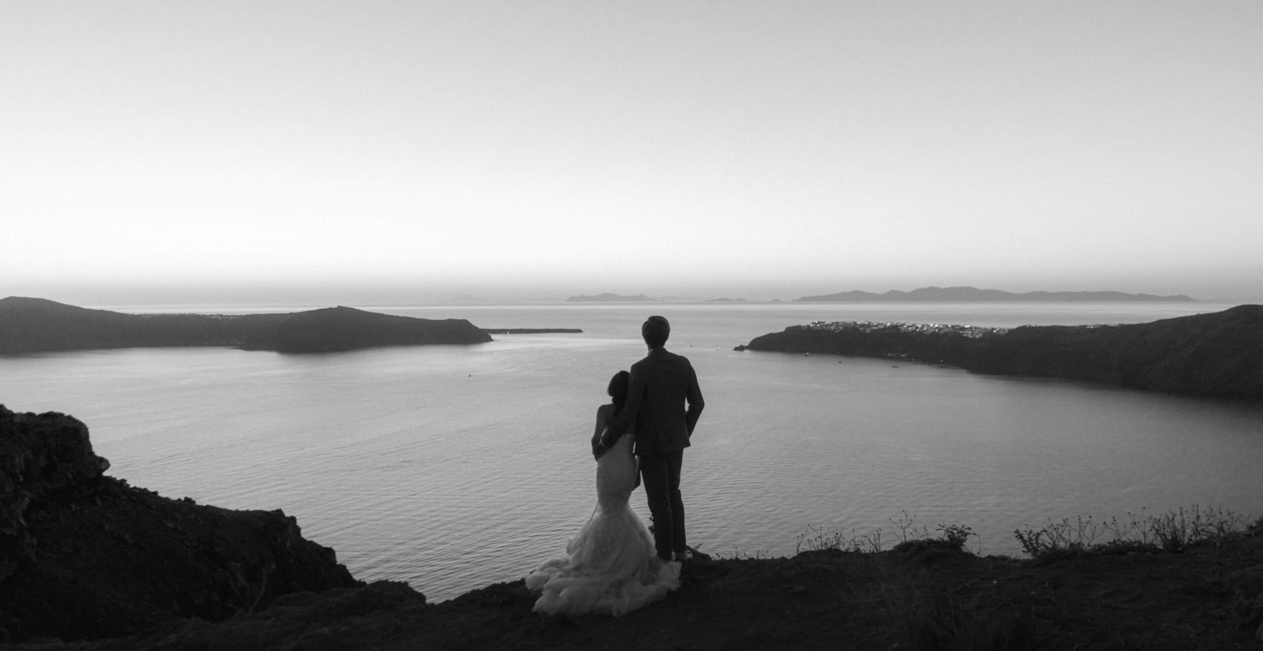 Couple silhouette at blue hour over the Santorini caldera.