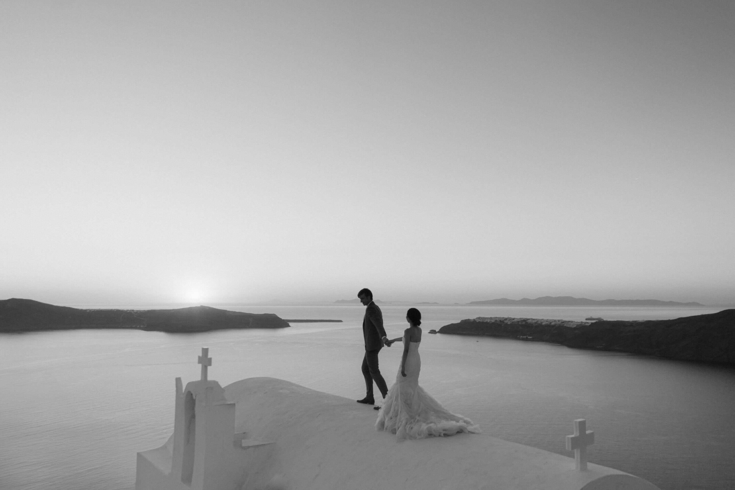 Couple alone on a Santorini rooftop path at dusk.